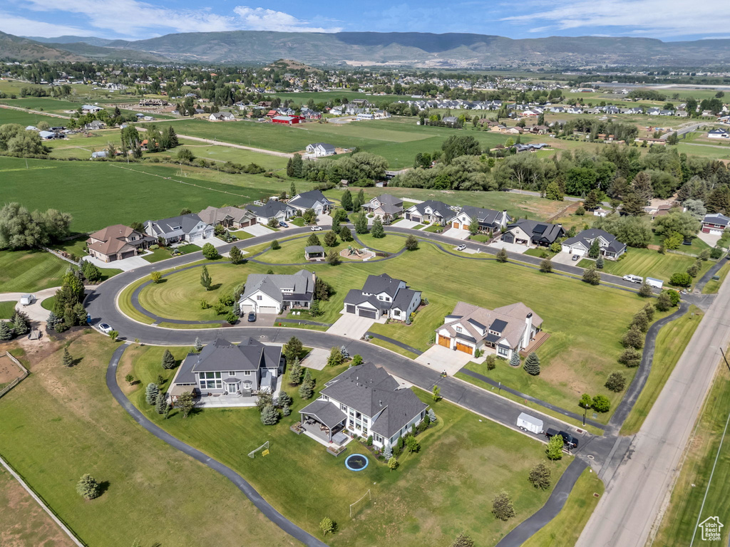 Aerial view of property and surrounding area featuring nearby suburban area and a mountain backdrop
