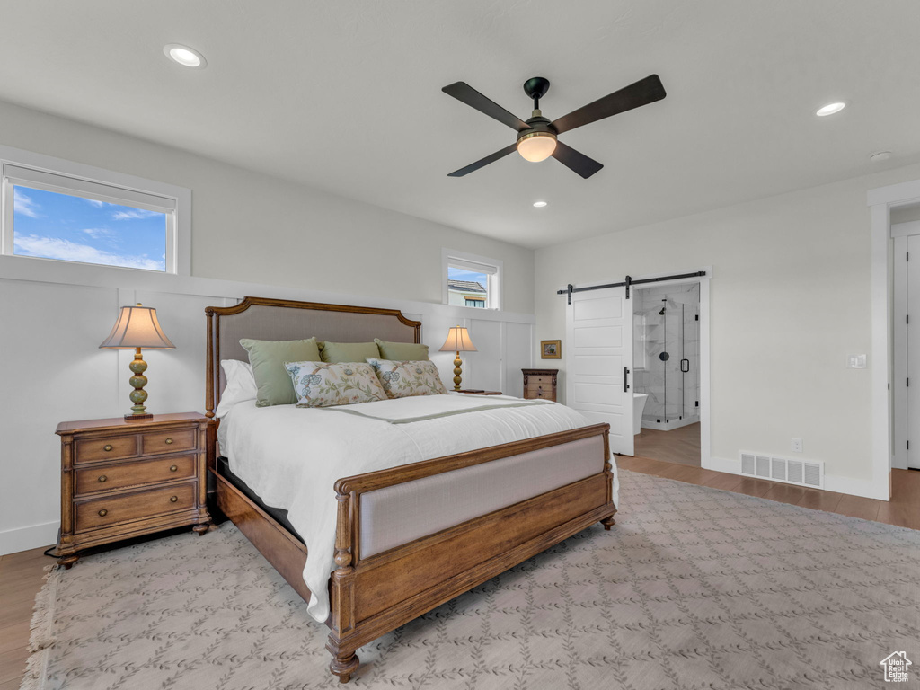 Bedroom featuring a barn door, wood finished floors, recessed lighting, a ceiling fan, and baseboards