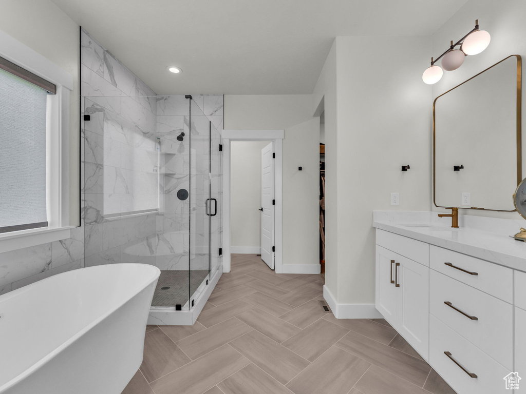 Full bath with vanity, a freestanding tub, a marble finish shower, baseboards, and recessed lighting