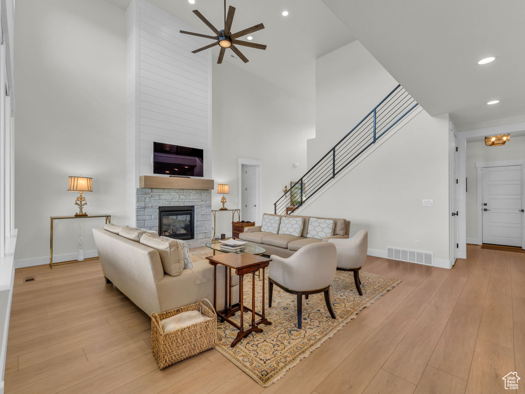Living area featuring a high ceiling, a stone fireplace, a ceiling fan, baseboards, and recessed lighting