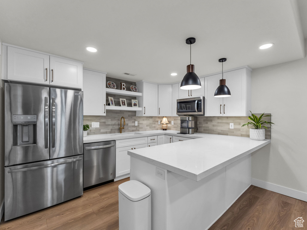 Kitchen with stainless steel appliances, a sink, open shelves, a peninsula, and tasteful backsplash