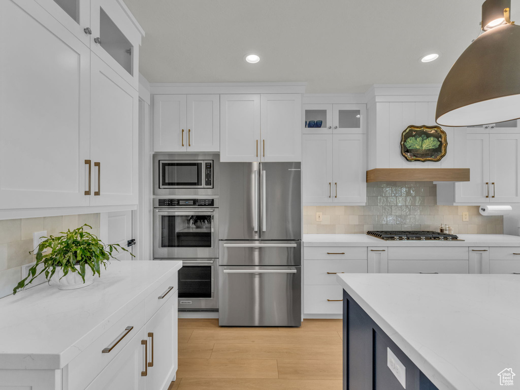 Kitchen with appliances with stainless steel finishes, light countertops, white cabinets, and recessed lighting