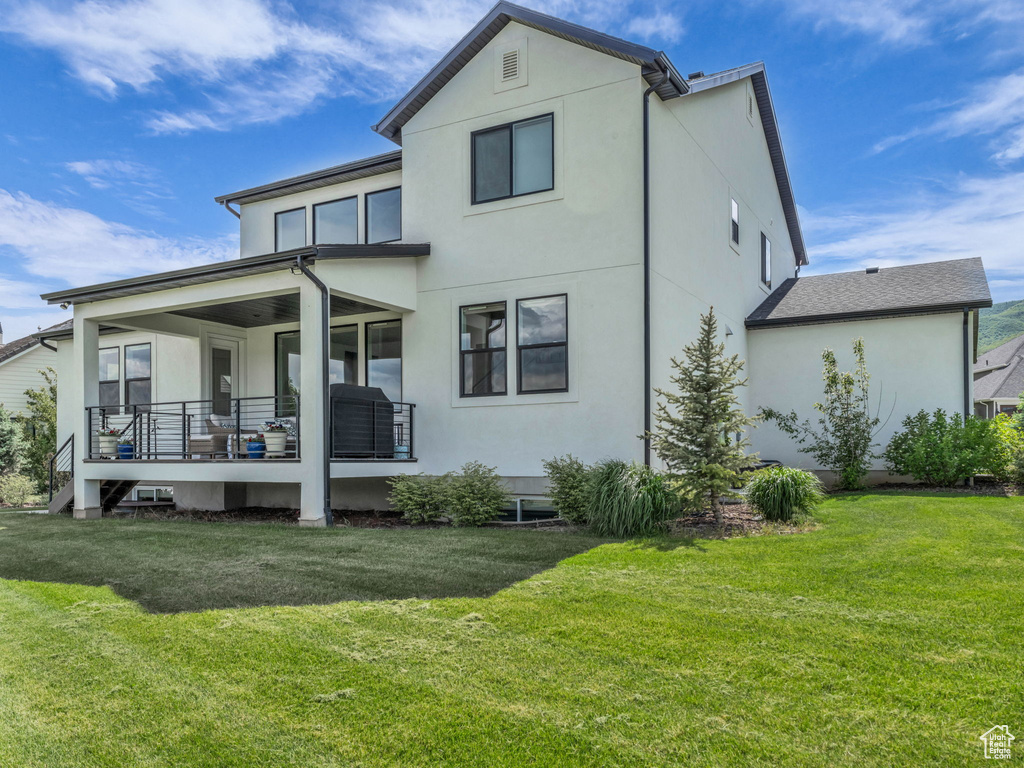 Rear view of property featuring stucco siding, a yard, and covered porch