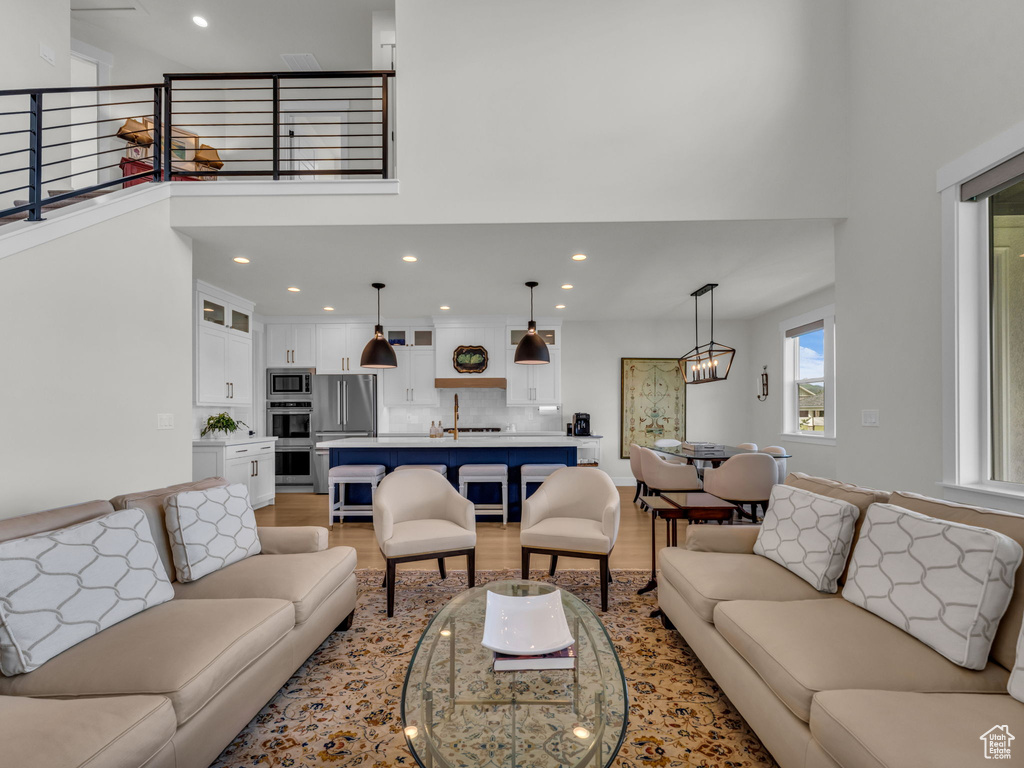 Living room featuring light wood finished floors, a towering ceiling, and recessed lighting