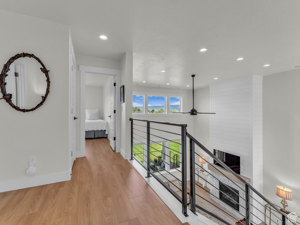 Hall featuring light wood-style flooring, recessed lighting, baseboards, and an upstairs landing