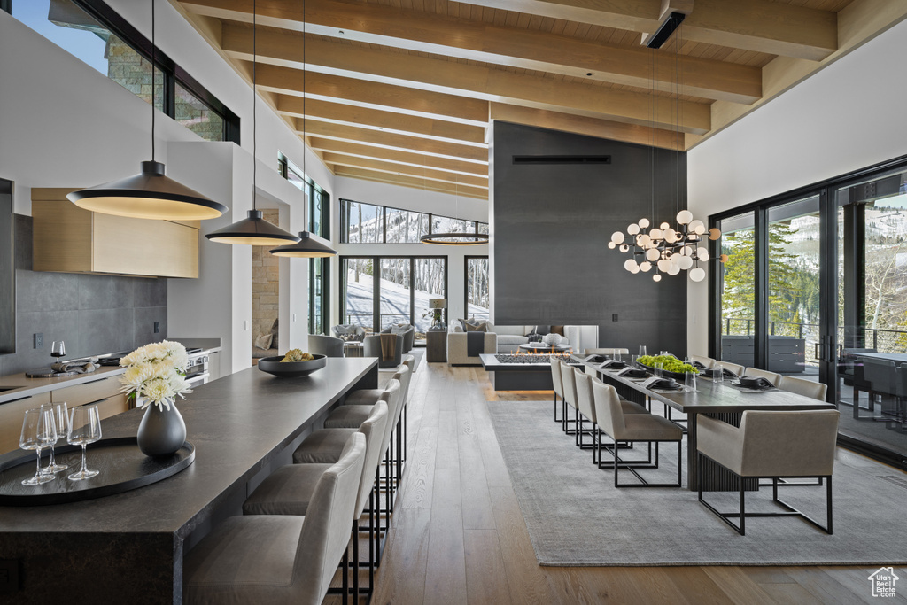 Dining room with a high ceiling, hardwood / wood-style floors, wooden ceiling with exposed beams, and healthy amount of natural light