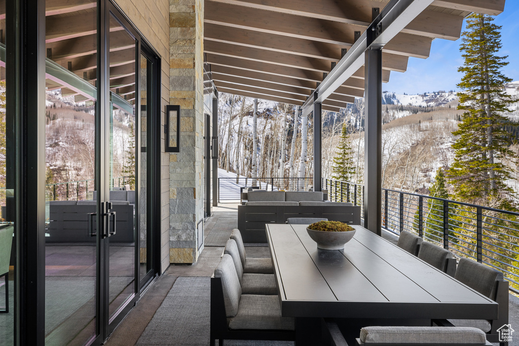 Snow covered back of property featuring outdoor dining area and a mountain view