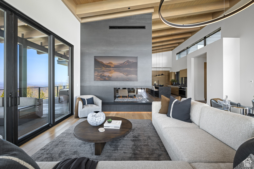 Living area with a towering ceiling, wood finished floors, and beam ceiling