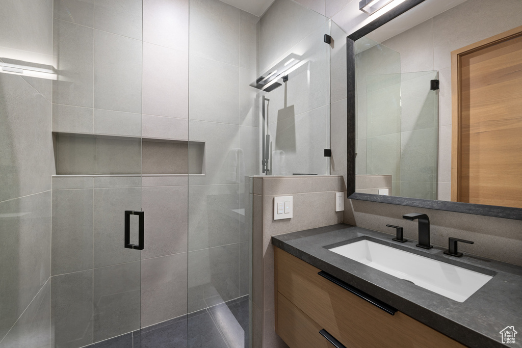 Full bathroom featuring a shower stall, vanity, and tile walls