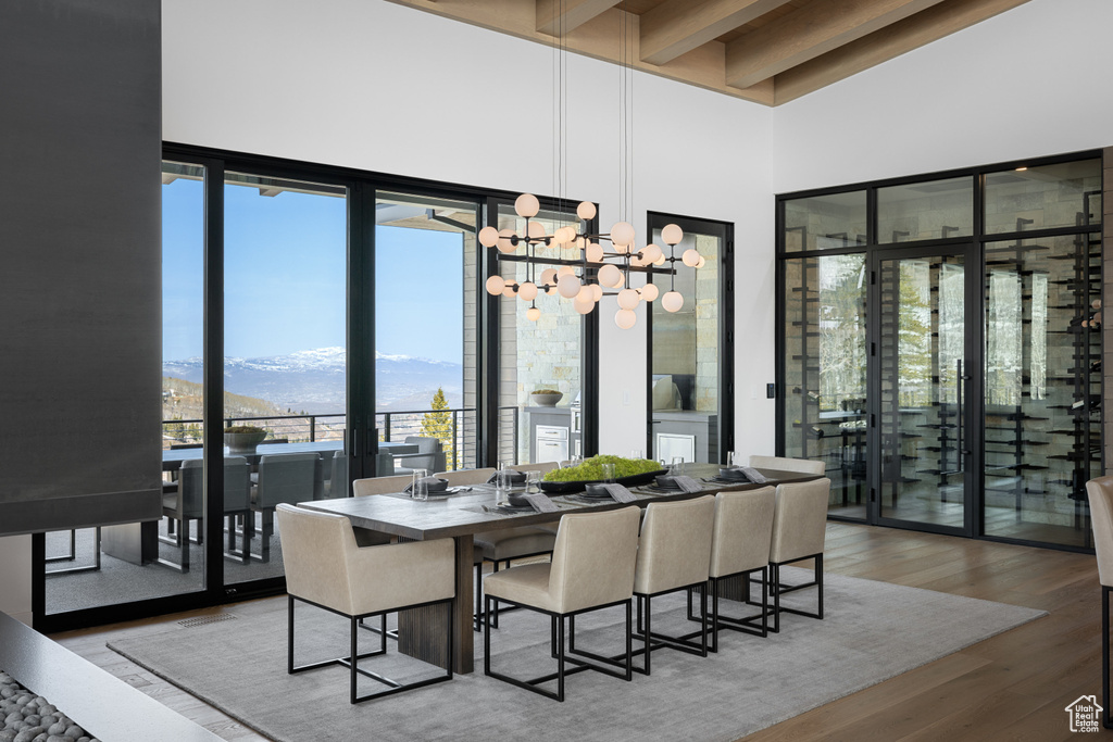 Dining area featuring a mountain view, a towering ceiling, wood finished floors, beamed ceiling, and a chandelier