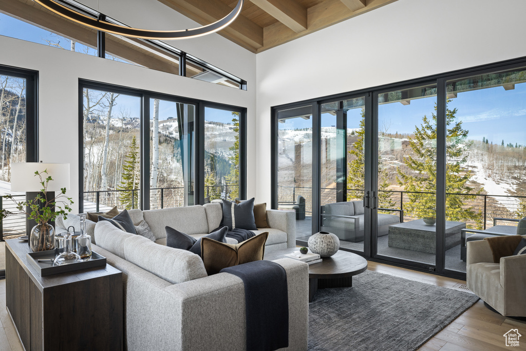 Living room with wood finished floors, a towering ceiling, and wood ceiling with exposed beams