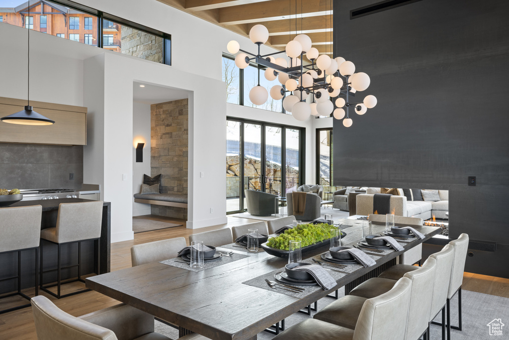 Dining room with a towering ceiling, wood finished floors, a chandelier, and beam ceiling