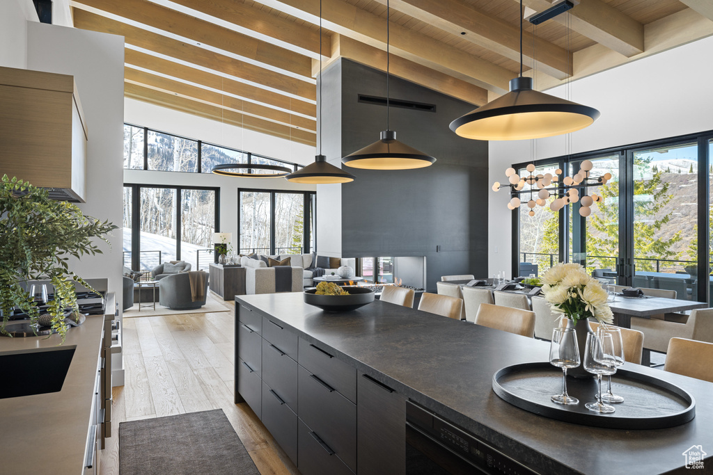 Kitchen featuring open floor plan, wooden ceiling with exposed beams, a towering ceiling, wood finished floors, and dark countertops