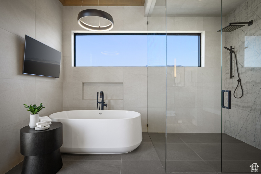 Bathroom with a soaking tub, a tile shower, tile walls, and tile patterned floors