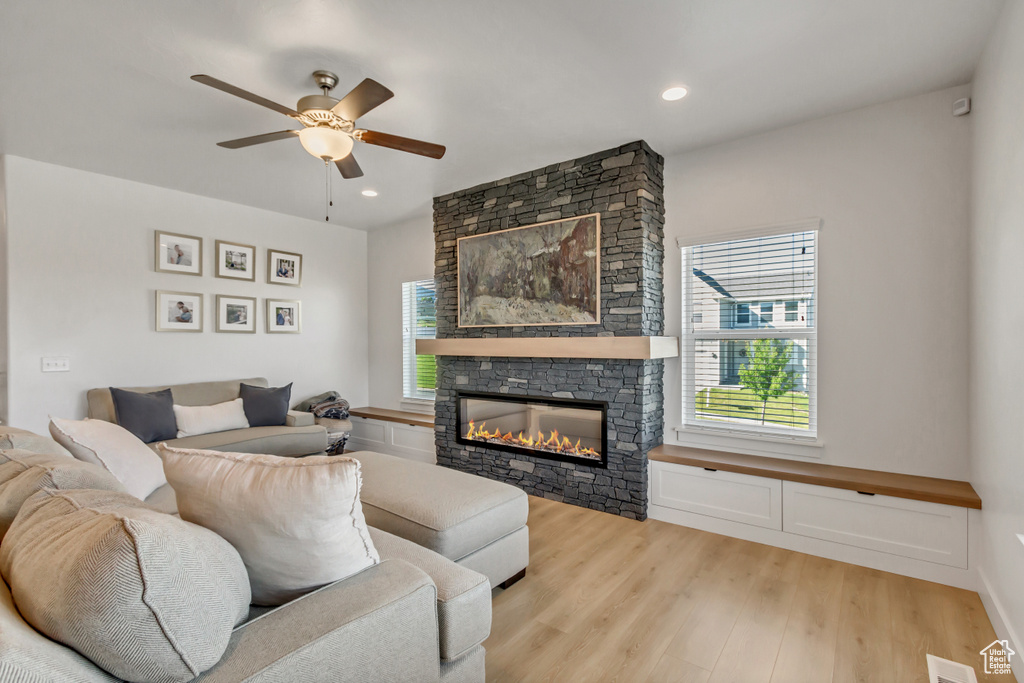 Living area with plenty of natural light, ceiling fan, light wood-type flooring, a stone fireplace, and recessed lighting