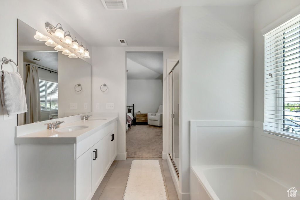 Full bathroom featuring connected bathroom, healthy amount of natural light, a garden tub, and double vanity