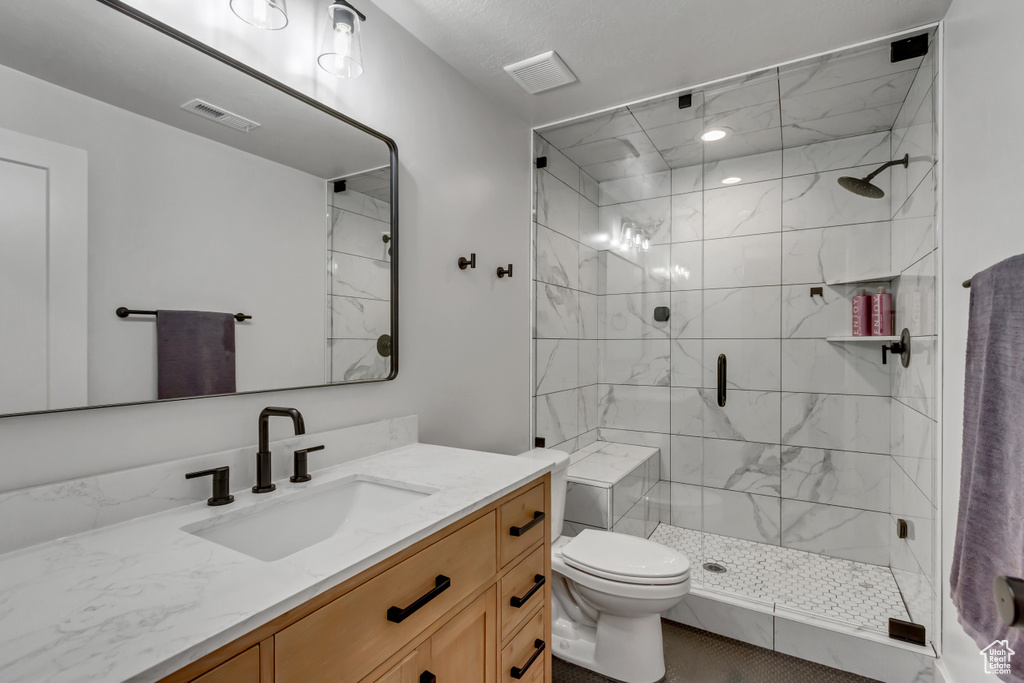 Bathroom featuring vanity, a stall shower, and toilet