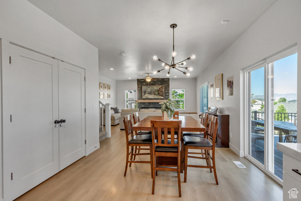 Dining room featuring light wood-style flooring, a chandelier, recessed lighting, a fireplace, and baseboards