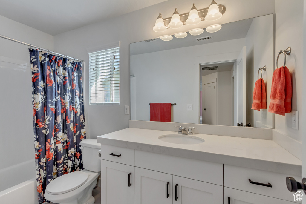 Bathroom with vanity, toilet, and shower / bath combination with curtain