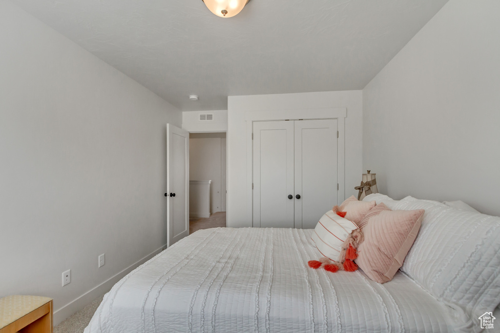 Carpeted bedroom with baseboards and a closet