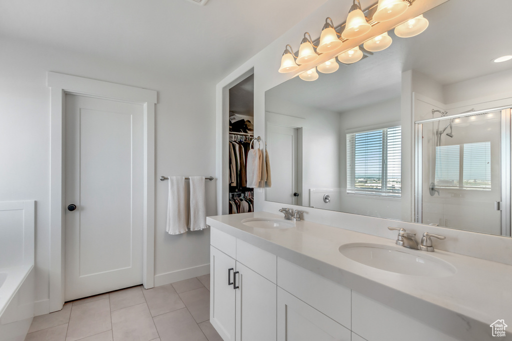 Full bath with a stall shower, double vanity, tile patterned floors, a bath, and a spacious closet