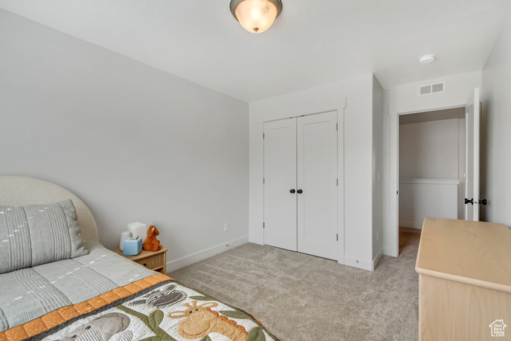 Bedroom featuring light carpet, baseboards, and a closet