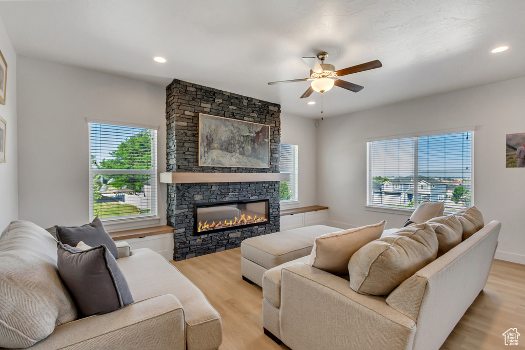 Living area featuring a ceiling fan, light wood-style flooring, a stone fireplace, and recessed lighting