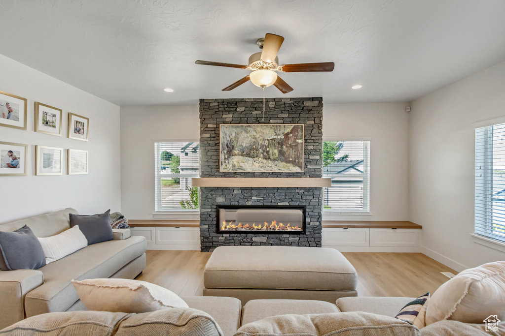 Living area with light wood finished floors, a ceiling fan, a fireplace, and recessed lighting