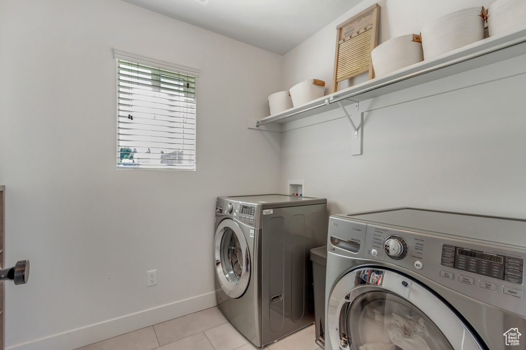 Laundry area featuring washer and dryer, light tile patterned floors, and baseboards