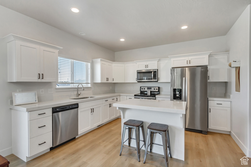 Kitchen featuring stainless steel appliances, a sink, white cabinets, light countertops, and recessed lighting