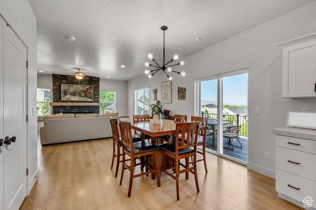 Dining room with light wood-style floors, a large fireplace, recessed lighting, a chandelier, and ceiling fan