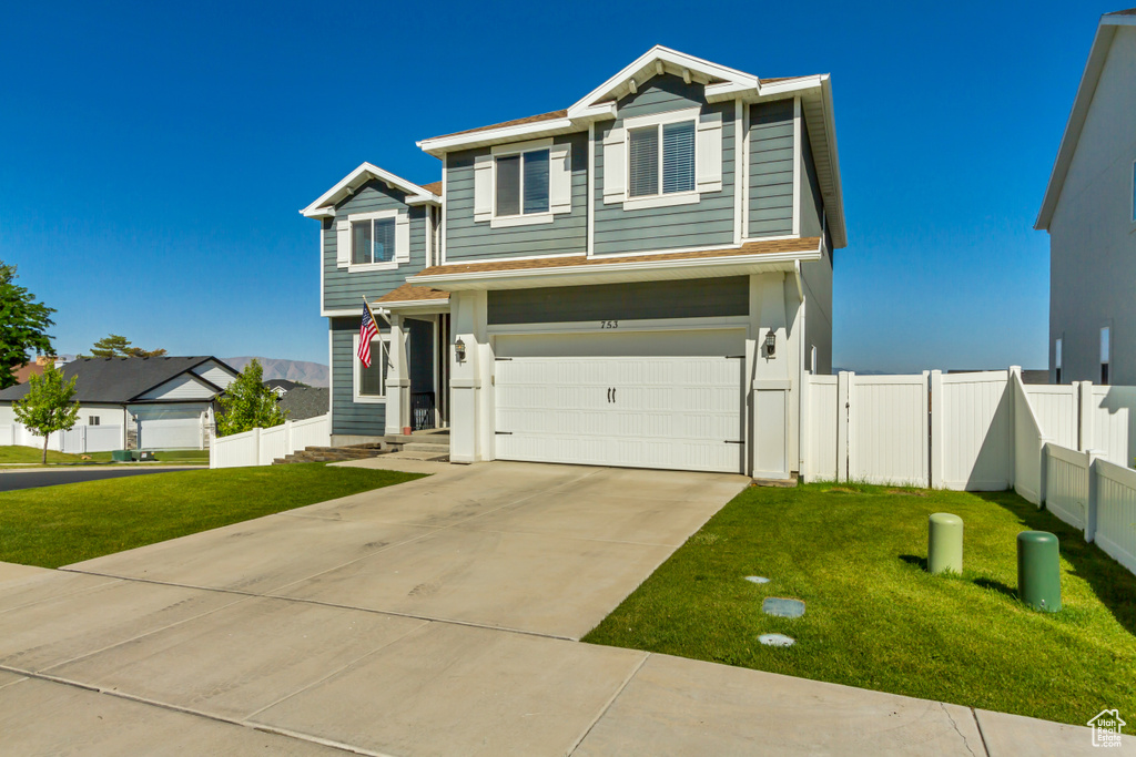 View of front of property with an attached garage, driveway, and a shingled roof