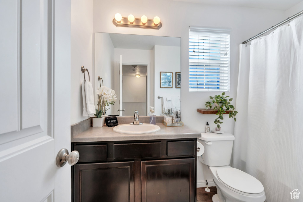 Full bath featuring toilet, vanity, and curtained shower