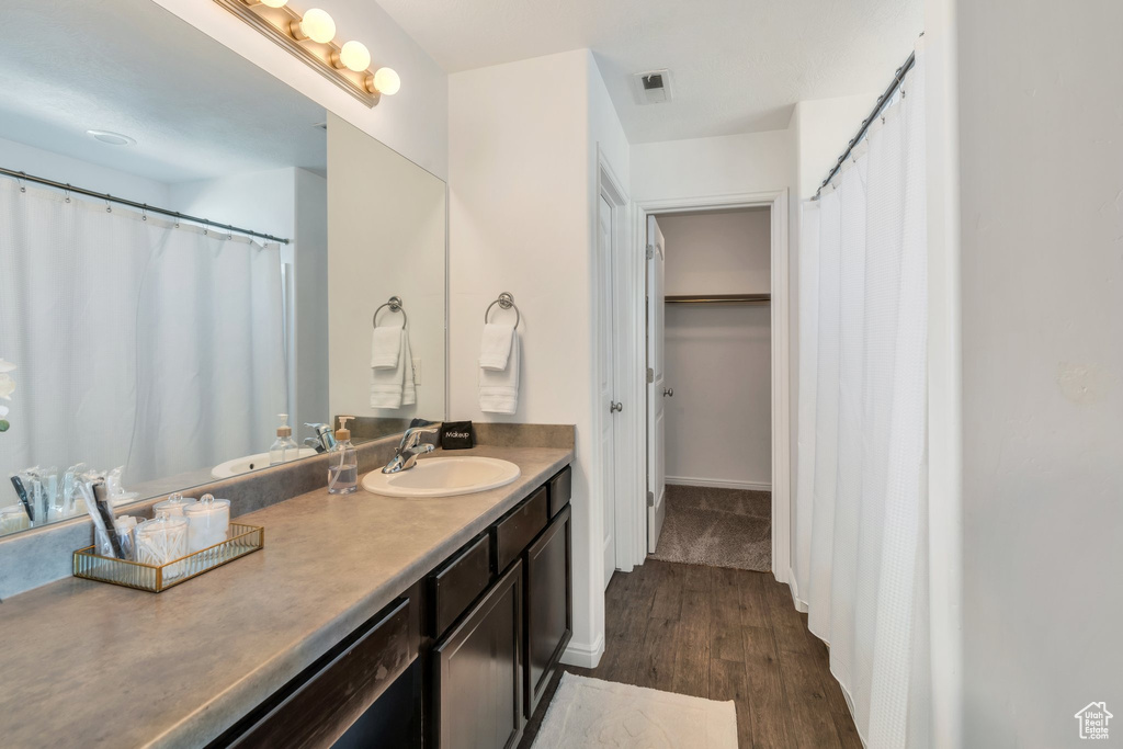 Full bathroom featuring wood finished floors, vanity, and baseboards