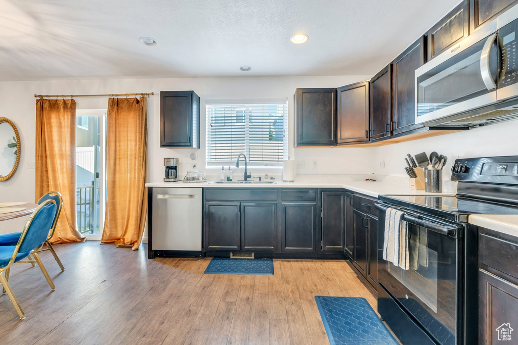 Kitchen featuring stainless steel appliances, a sink, light countertops, light wood-style floors, and recessed lighting