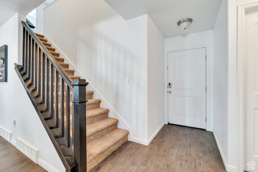Entryway featuring wood finished floors, baseboards, and stairs