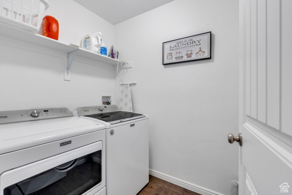 Washroom featuring washer and clothes dryer, dark wood-style floors, and baseboards