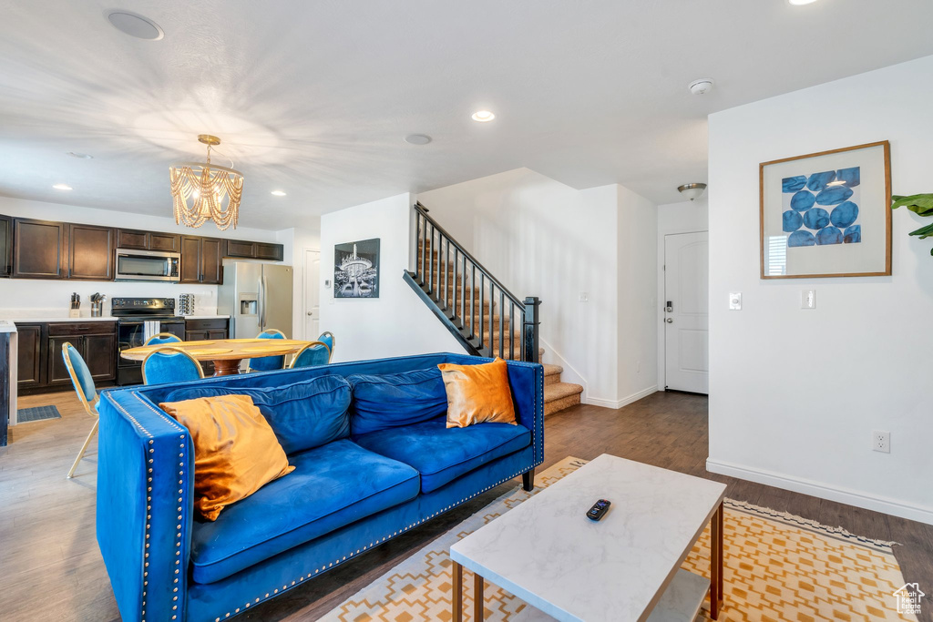 Living room with a chandelier, stairs, wood finished floors, recessed lighting, and baseboards