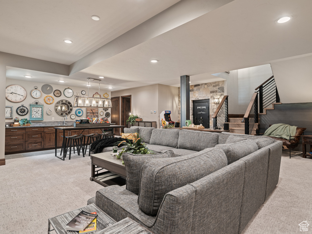 Living room featuring bar with sink, light carpet, recessed lighting, and stairs