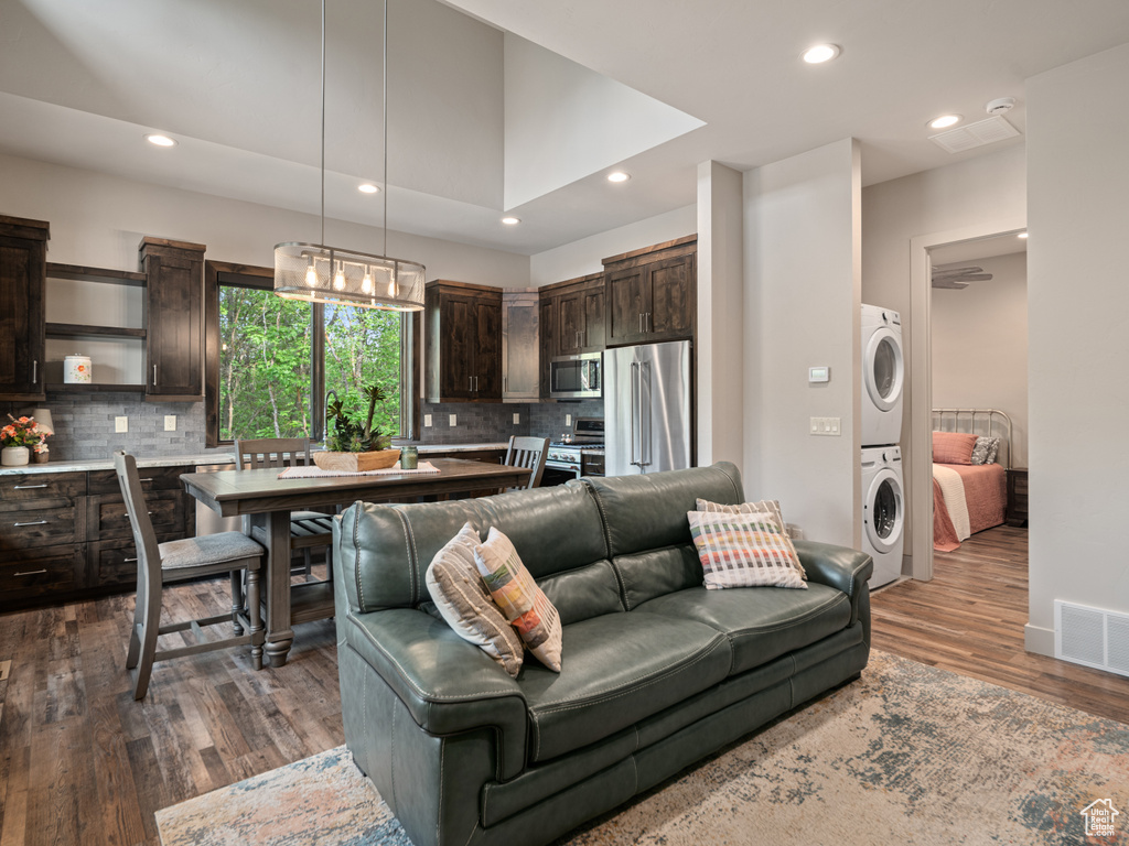Living area featuring stacked washer / dryer, dark wood-style flooring, and recessed lighting