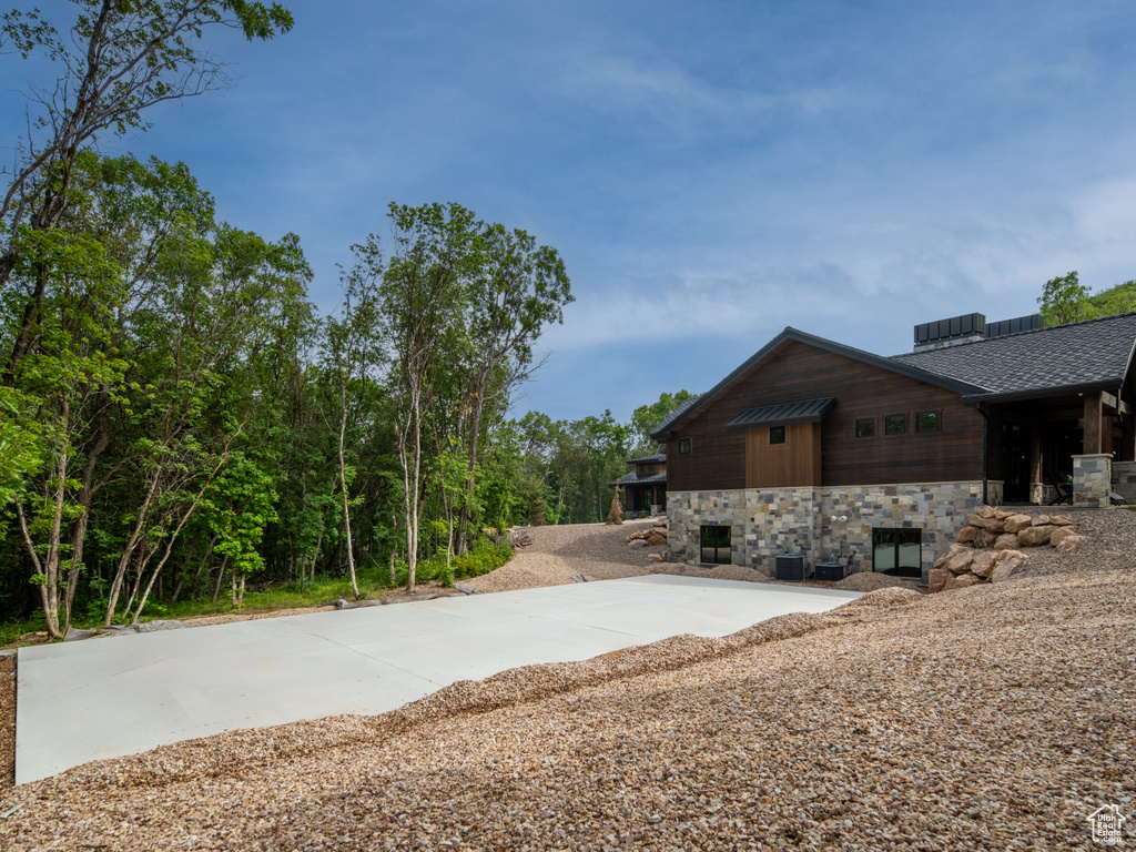 View of property exterior featuring stone siding and a shingled roof