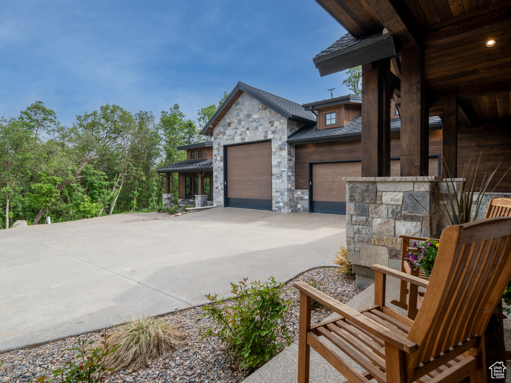 View of side of home featuring stone siding and driveway