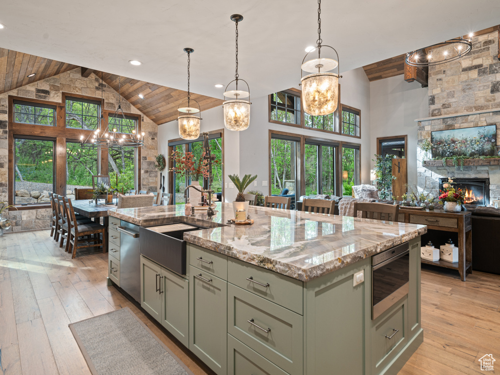 Kitchen featuring high vaulted ceiling, open floor plan, a sink, dishwasher, and light stone countertops