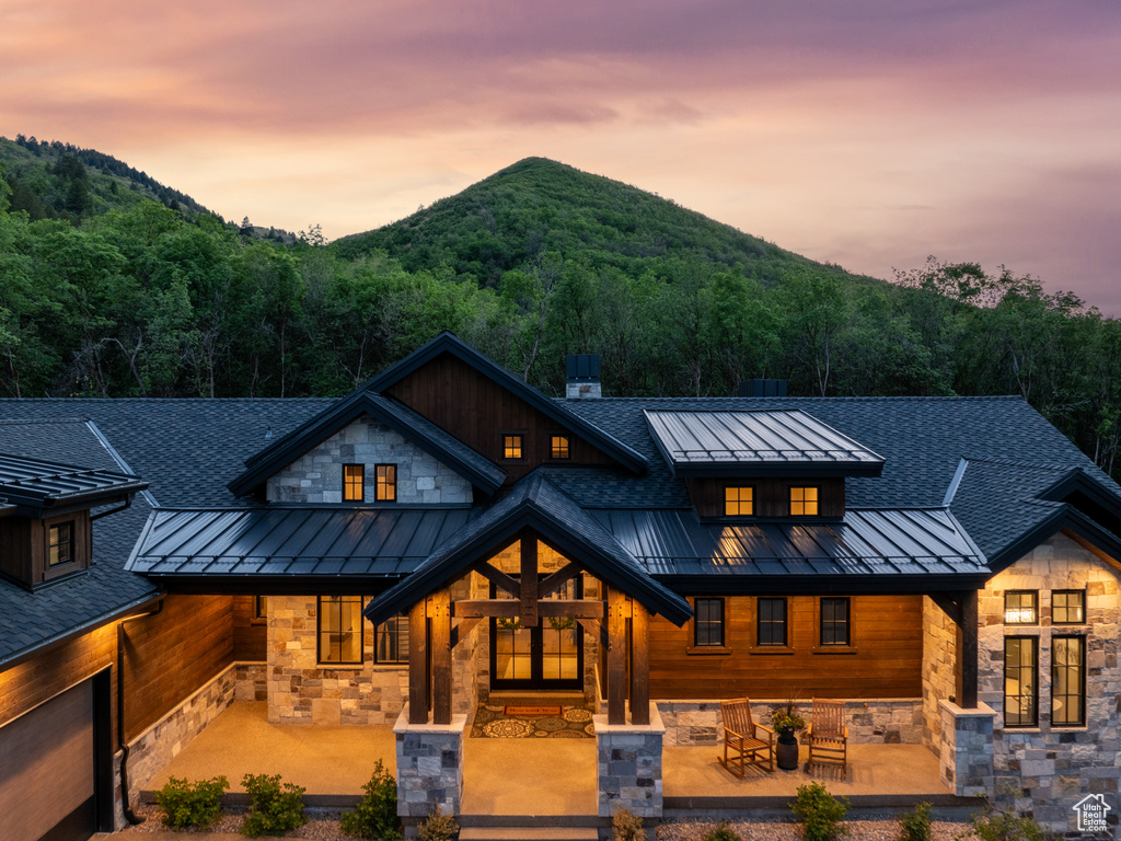 Modern farmhouse style home with a standing seam roof, metal roof, stone siding, and roof with shingles