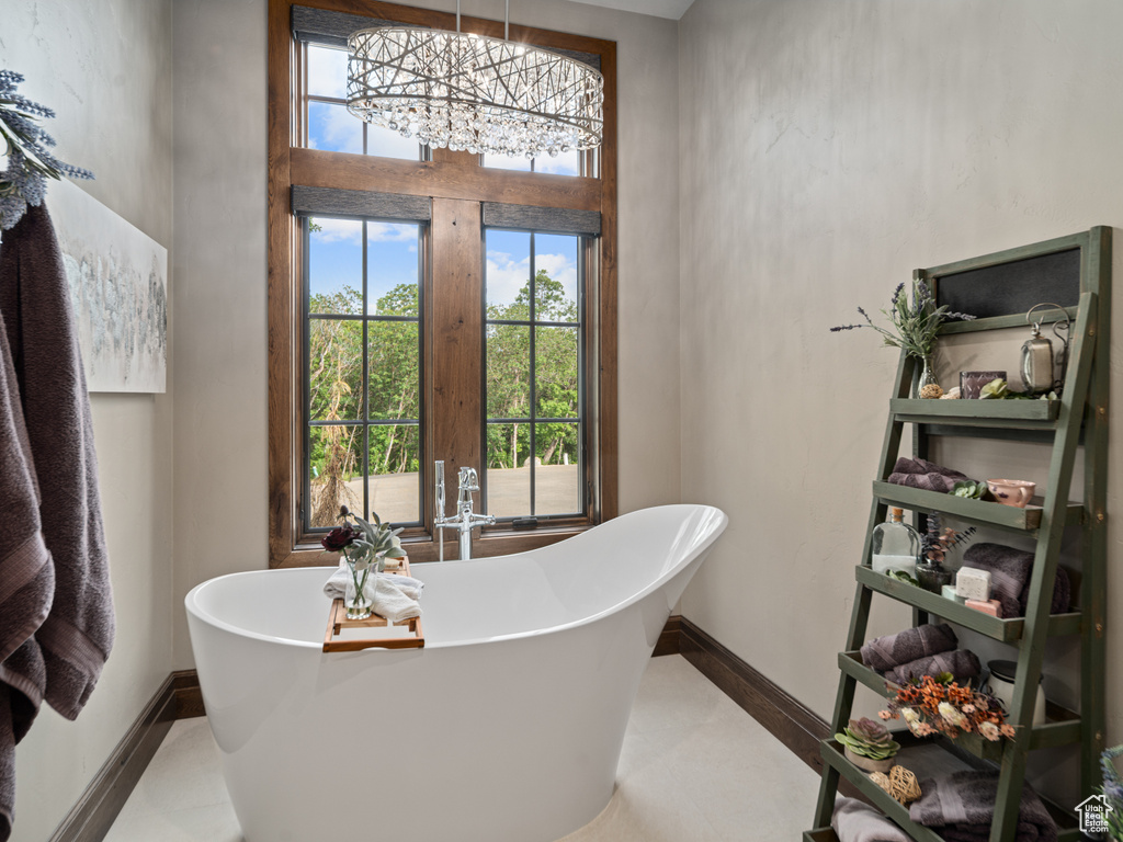 Full bathroom with a soaking tub, a chandelier, baseboards, and tile patterned flooring