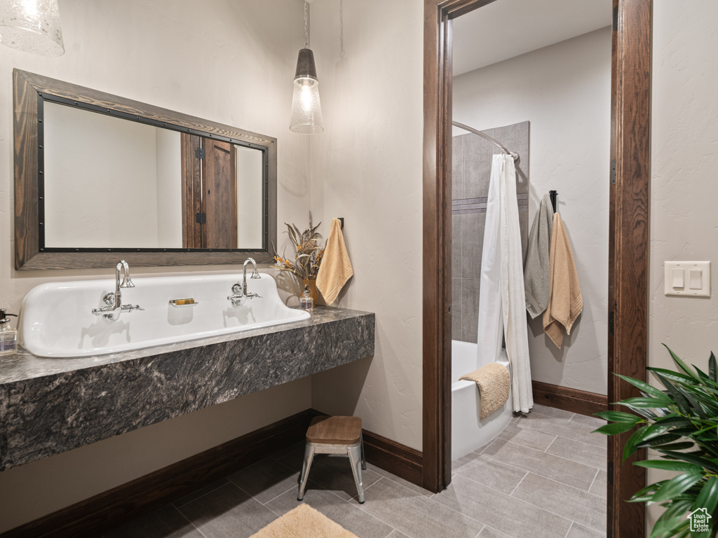 Full bathroom with tile patterned floors, shower / bath combo, baseboards, and a sink