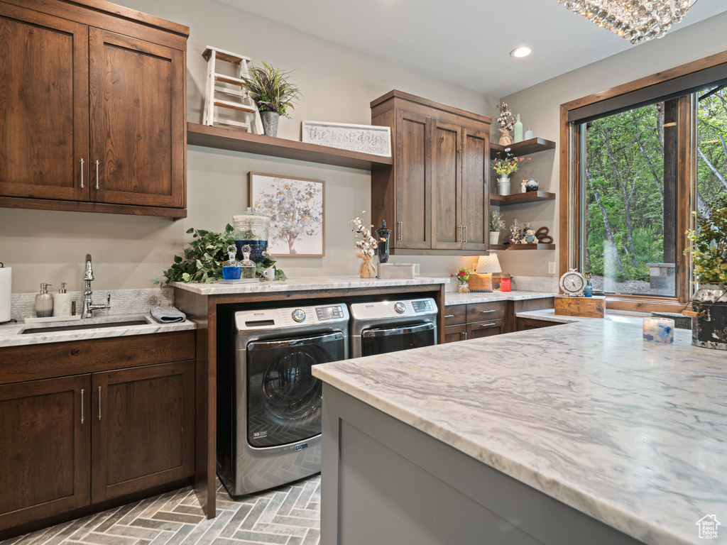 Washroom featuring washer and clothes dryer, brick patterned floors, recessed lighting, and cabinet space
