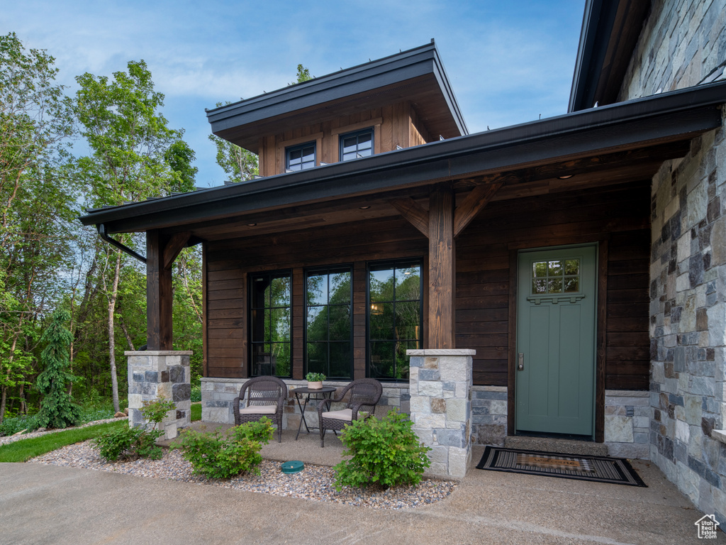 Doorway to property with stone siding and a porch
