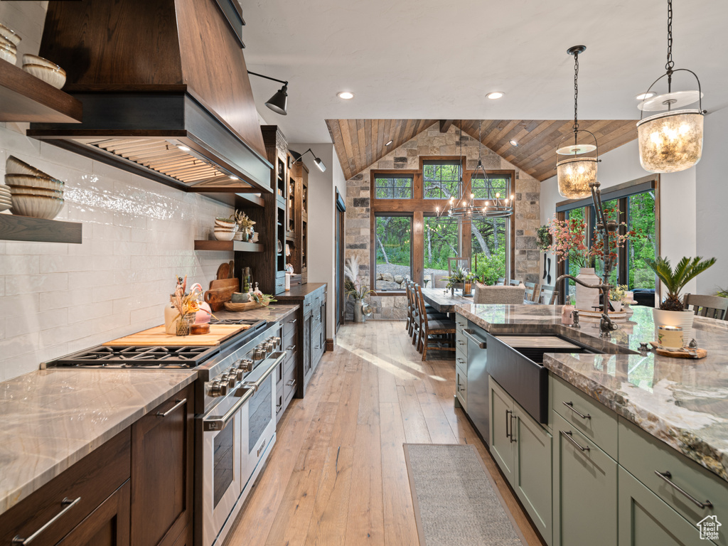 Kitchen featuring open shelves, appliances with stainless steel finishes, a sink, lofted ceiling, and plenty of natural light