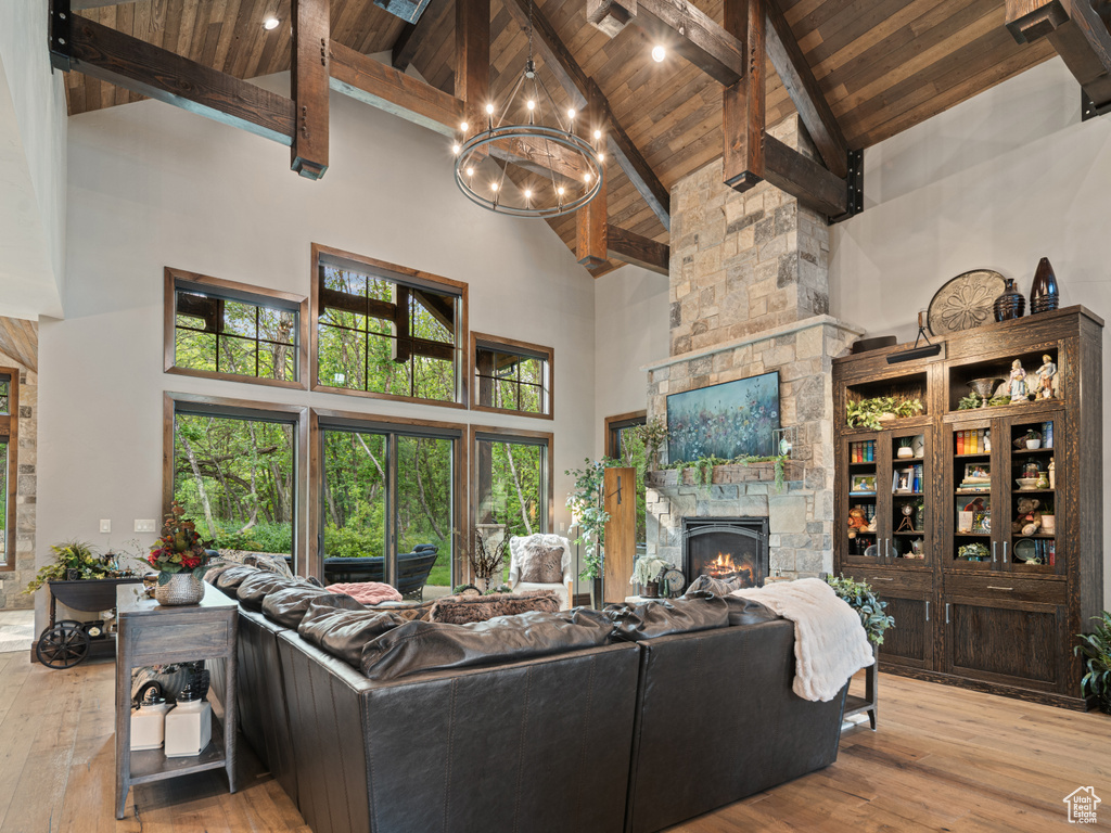 Living area with wood ceiling with exposed beams, high vaulted ceiling, hardwood / wood-style floors, a fireplace, and a chandelier